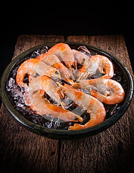 Frozen shrimp with ice cubes on a wood background