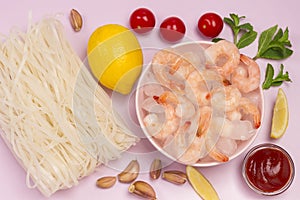 Frozen shrimp and ice in pink bowl. Rice noodles, lemon, mint garlic, tomato sauce