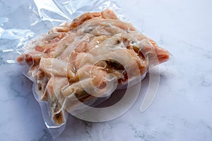 Frozen shrimps in vacuum transparent plastic packaging bag on white table background. Top view, copy space