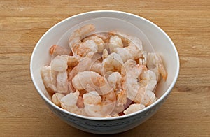 Frozen shrimps in a white bowl, isolated on wooden background