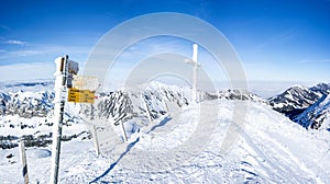 frozen signpost and cross at the summit of the snowy mountain. gorgeous mountain panorama in switzerland on fuerstein, swiss alps