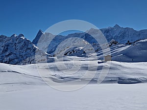 A frozen and snow covered Bachalpsee lake with a mountain hut and Grindelwald alps view in sunny weather winter