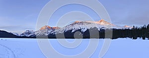 Frozen Snow Covered Mountain Lake and Distant Mountain Peaks Panoramic Winter Landscape in Canadian Rockies