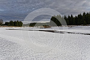 Frozen snowy lake near forest