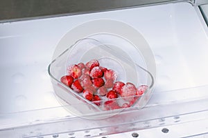 Frozen strawberries in a container in the freezer