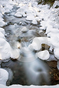 Frozen stream in winter forest.