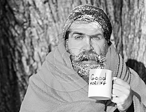 Frozen surprised man, bearded hipster, with beard and moustache covered with white frost and orange blanket with warming