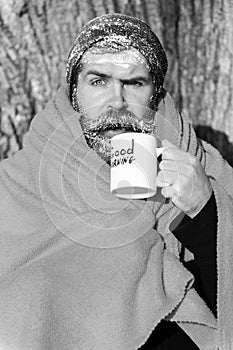 Frozen surprised man, bearded hipster, with beard and moustache covered with white frost and orange blanket with warming