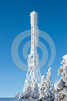 Frozen television or cellular tower in heavy snow near ski center. Telecommunication towers with dish and mobile antenna against