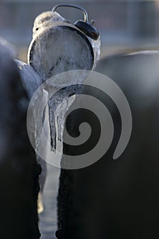 Frozen time. A clock frozen in ice. Extreme weather situation. Daylight saving time shift. Vertical photo