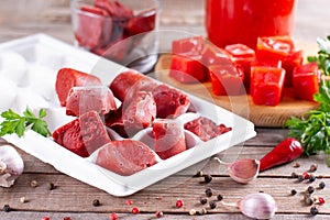 Frozen tomato paste in the plastic shape on wooden background. Life hacks, simple way to store vegetables