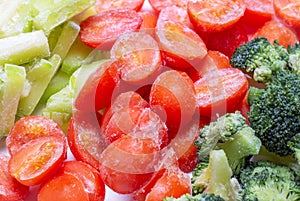 Frozen tomatoes, vegetable marrows and broccoli close-up, top view