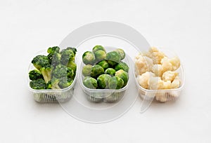 Frozen vegetables cabbage mix in containers on a white background. Brussels sprouts, broccoli, cauliflower