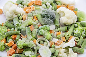 Frozen vegetables: cauliflower, green peas, leeks, broccoli, carrots, green beans on a white plate