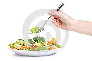 Frozen vegetables on plate fork in hand