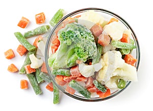 Frozen vegetables in a plate and sprinkled on a white. Top view.