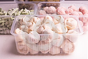 Frozen vegetables and semi-finished meat products in plastic containers on a white plate. meatballs, dumplings, chopped beans