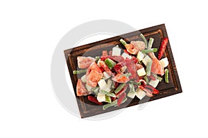 Frozen vegetables, tomatoes, string beans, zucchini, red pepper on wooden cutting board isolated on white background. Freezing,