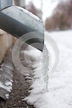 Frozen water in a drainpipe, with hanging icicles