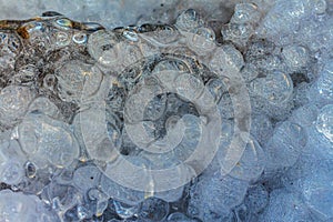 Frozen water drops with many air bubbles inside close-up. Bubble figured ice macro photography