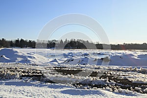 Frozen water and snow piles  blue sky tire marks in front