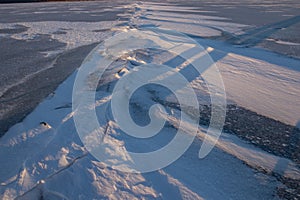 Frozen water surface with subtle ice texture and soft sunlight reflection creating calm abstract winter background