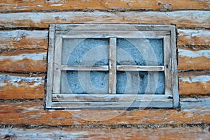 A frozen window in the hunter\'s house. Glass in ice in the forester\'s house in the taiga among the trees. Forest.