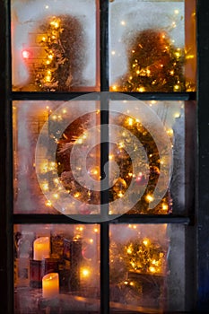 Frozen window with unfocused festive interior inside for decorative design. Holiday celebration.