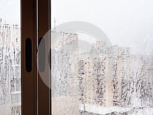 Frozen window in urban house in city in winter