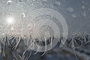 Frozen window in winter time. Frost pattern on the window. Icy flowers on a glass