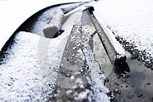 Frozen windshield wiper and glass on car. Close up frozen windshield. Frozen white car in winter. Ice on front window of a car