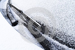 Frozen windshield wiper and glass on car. Close up frozen windshield. Frozen white car in winter. Ice on front window of a car