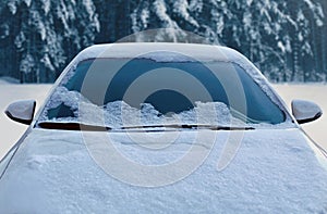 Frozen winter car covered snow, view front window windshield and hood on snowy forest