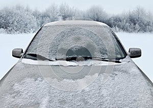 Frozen winter car covered snow, view front window windshield and hood on snowy forest