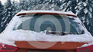 Frozen winter car covered snow, view rear window windshield on snowy forest background