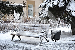 Frozen winter city landscape with snow-covered bench