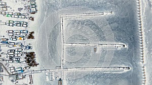 frozen in winter ice lake, docked in pier, aerial top down view