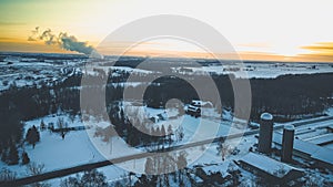 Frozen winter landscape with smoke plume and barn with silo