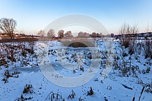 Frozen winter river, sprinkled with snow, reeds