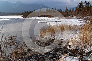 Frozen winter scene at Vermillion Lakes parkway in Banff National Park, with snow covered grasses, open hot springs water, and
