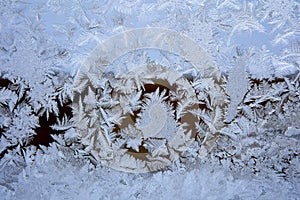 Frost patterns on frozen glass of winter window.