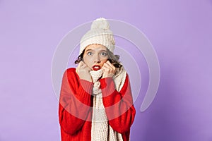 Frozen woman wearing winter hat and scarf isolated over purple background
