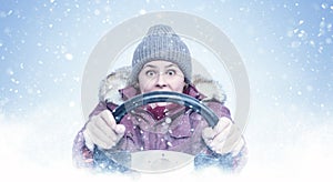 A frozen woman in winter clothes is driving a car, steering wheel in hand, snow is falling on a blue background, front view.