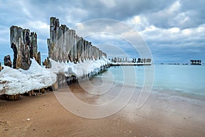 Frozen wooden breakwaters line to the world war II torpedo platform at Baltic Sea