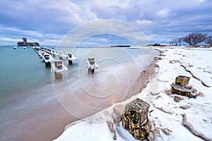 Frozen wooden breakwaters line to the world war II torpedo platform at Baltic Sea