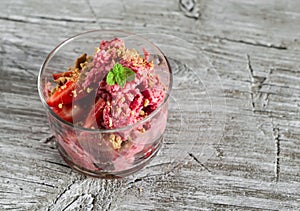 Frozen yogurt with strawberries and cookie crumbs in a glass bowl