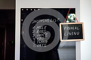 Frugal living, save money, live cheap concept with shopping list on letterboard and Frugal living text in frame in