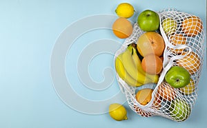 Fruit banana apples oranges lemon in caton mesh , string shopping bag on a blue background. zero waste concept. No plastic.