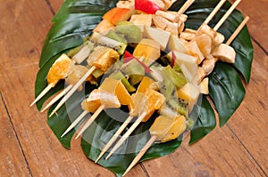 Fruit barbecue on leaf of monstera and wooden background