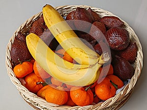 Fruit basket filled with bananas, snakefruit, and oranges